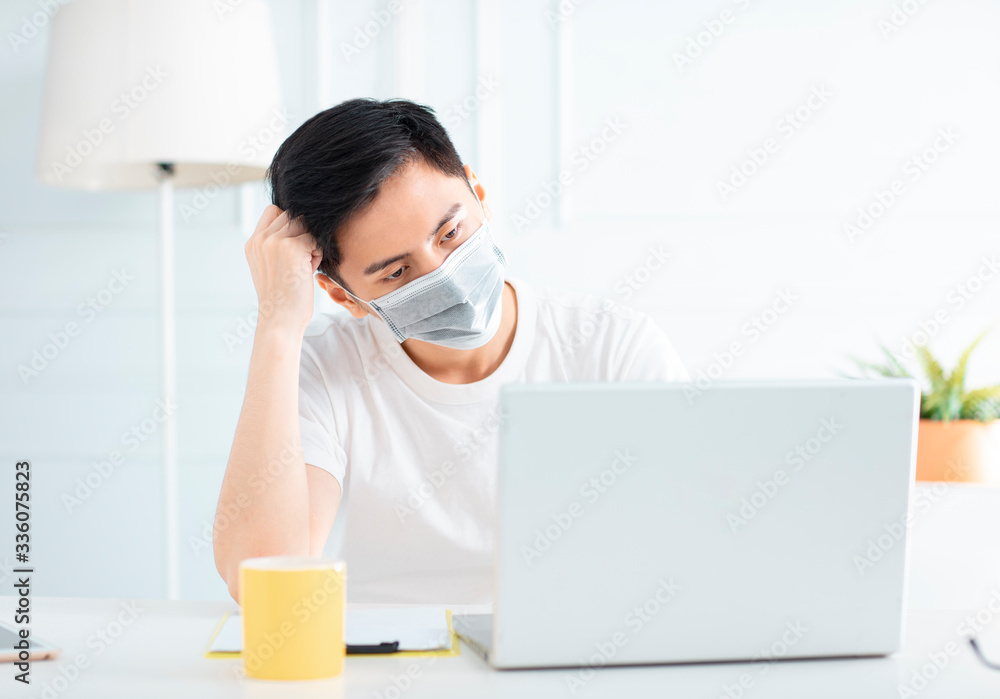 young businessman wear mask and working with laptop at home young businessman wear mask and working with laptop at home