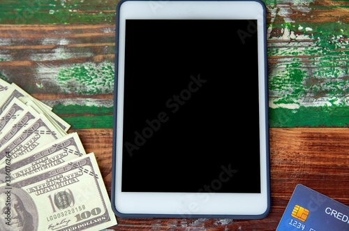 Fototapeta Naklejka Na Ścianę i Meble -  Dollar bills, credit card and digital devices tablet with technology and money on a wooden background