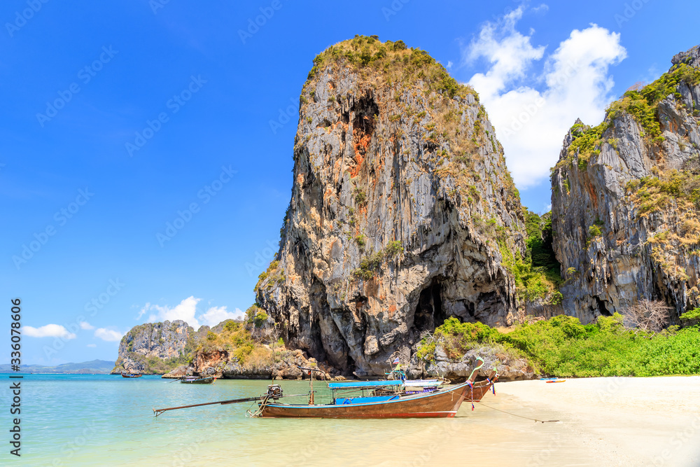 Fototapeta premium Long tail boat and turquoise crystal clear sea water with limestone cliff and mountain at Phra Nang Beach, Krabi, Thailand