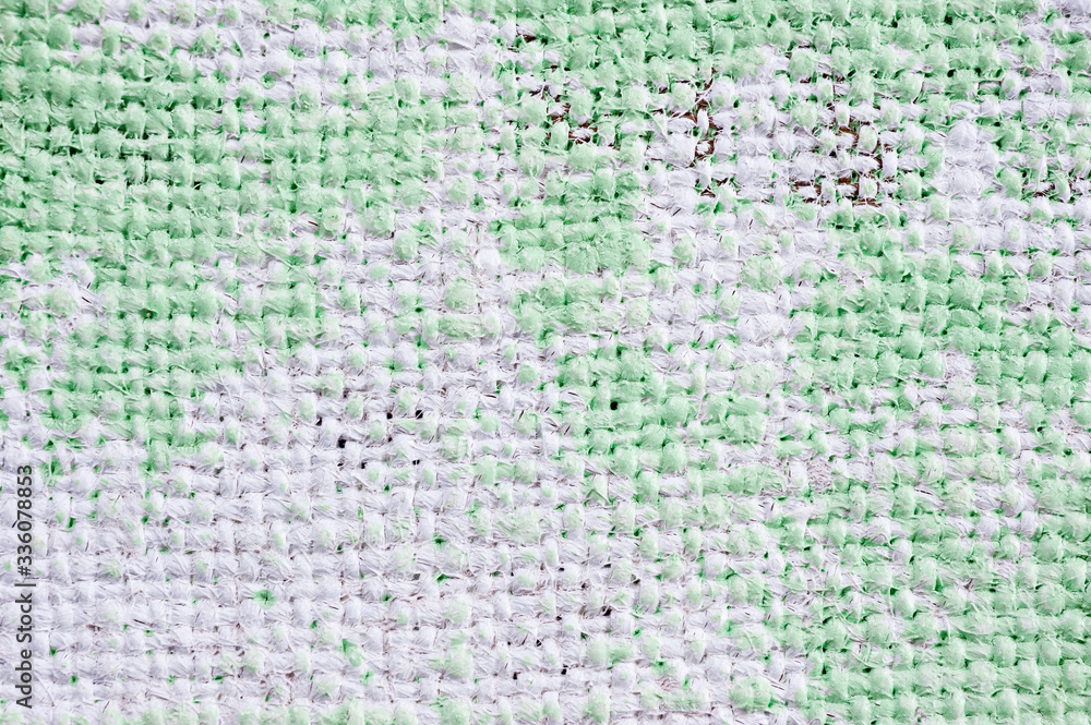Closeup texture of a roughly painted white and light green canvas lying on a wooden surface. Background for fabric texture. Universal background. Closeup texture of a roughly painted white and light green canvas lying on a wooden surface. Background for fabric texture. Universal background.