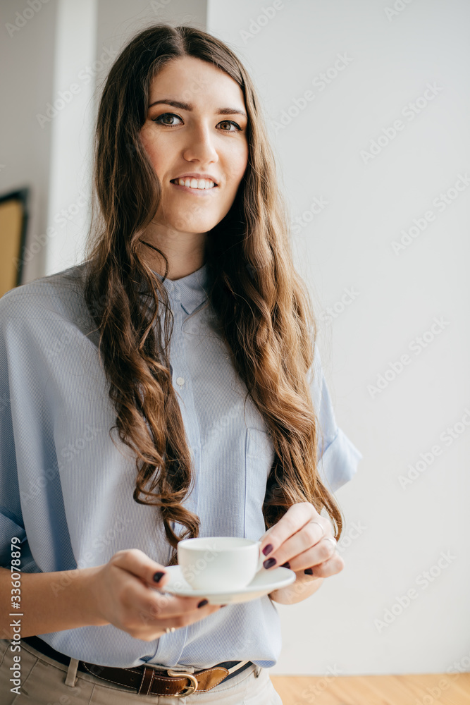 Portrait of a young woman by window with cup of tea Portrait of a young woman by window with cup of tea