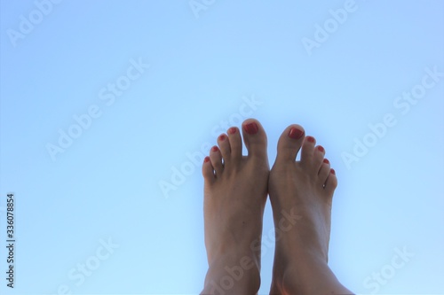 female feet with red pedicure on a background of blue sky