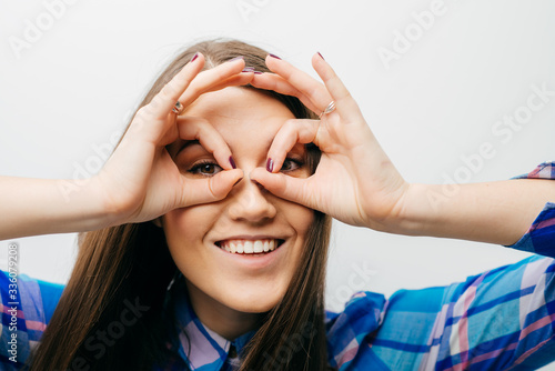 Young happy woman holding her hands over her eyes as glasses and looking through fingers