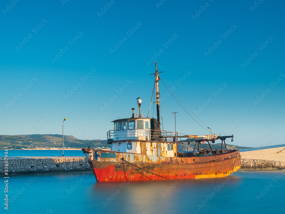 old ship in front of pier in long exposure of water in summer day