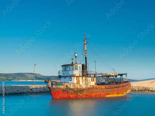 old ship in front of pier in long exposure of water in summer day