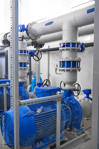 blue high-pressure pumps engines and gray pipes, water or wastewater treatment facilities inside, industrial interior