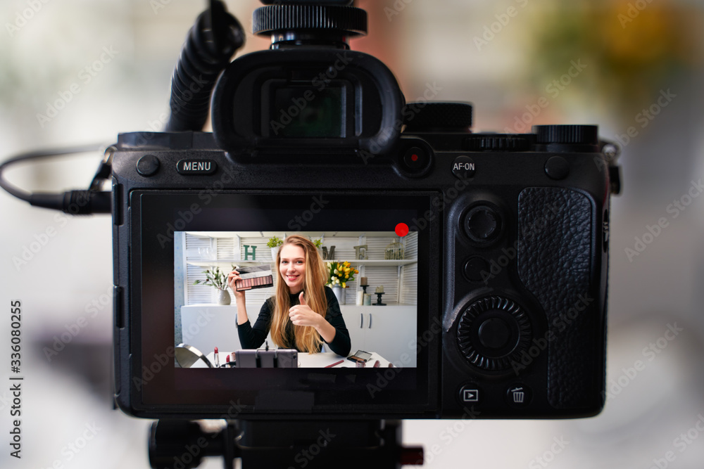 Display of camera recording video blog for blonde beauty blogger woman with make-up at home studio. Influencer vlogger girl live streaming cosmetics masterclass. Online learning and marketing concept. Display of camera recording video blog for blonde beauty blogger woman with make-up at home studio. Influencer vlogger girl live streaming cosmetics masterclass. Online learning and marketing concept.