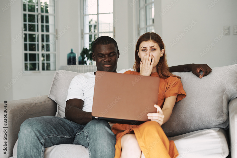 young couple sitting on sofa with laptop young couple sitting on sofa with laptop