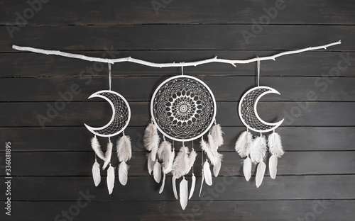 Photography White dream catcher with feather hanging at black wooden background