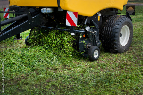 a new baler in motion work on the field creates bales from fresh silos at summer
