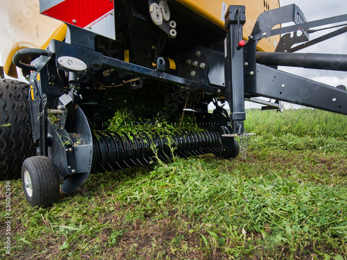 a new baler in motion gathers grass on the field creates bales
