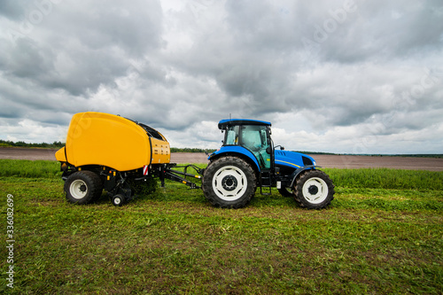 new blue tractor with baler in motion at field