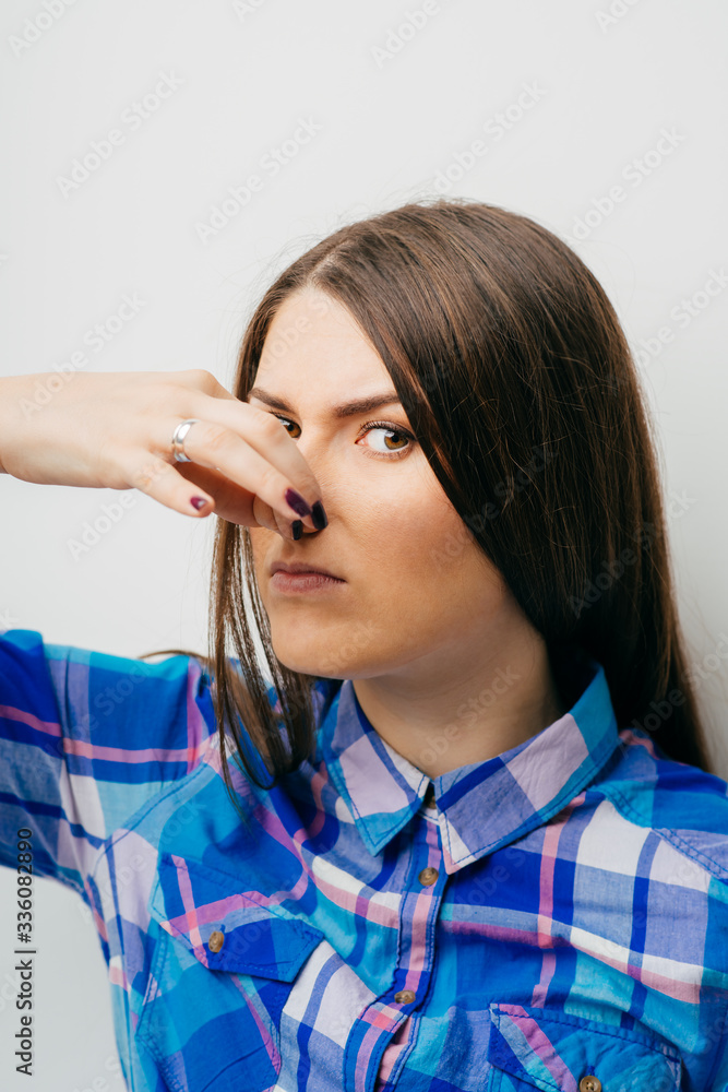 Beautiful young lady covers nose with hand showing that something ...