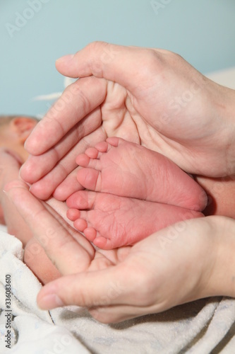 a small newborn baby in the arms of its mother, the mother holds the newborn's legs in her hands
