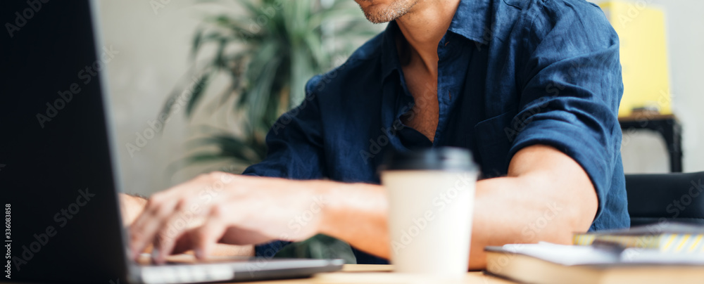 Fototapeta premium Man working on laptop at bright studio
