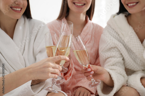 Foto Young ladies clinking glasses of champagne at pamper party, closeup