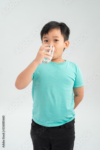 Young little Asian boy taking tablet medicine with a glass of water. Healthcare and Medical concept.