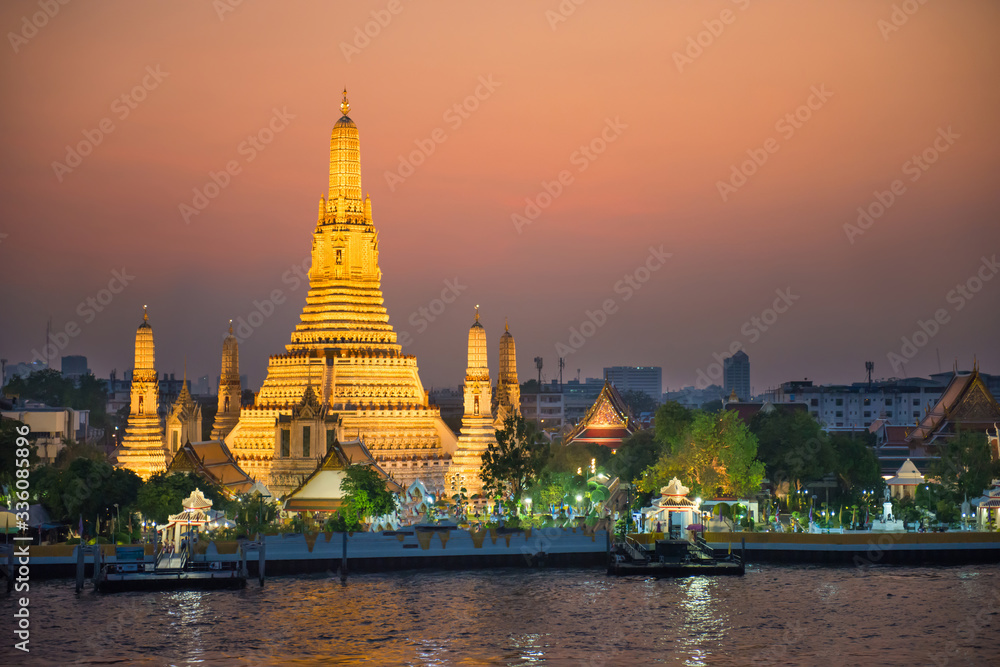 Illuminated Temple of Dawn or Wat Arun and Thonburi west bank of Chao Phraya River at sunset. Bangkok, Thailand