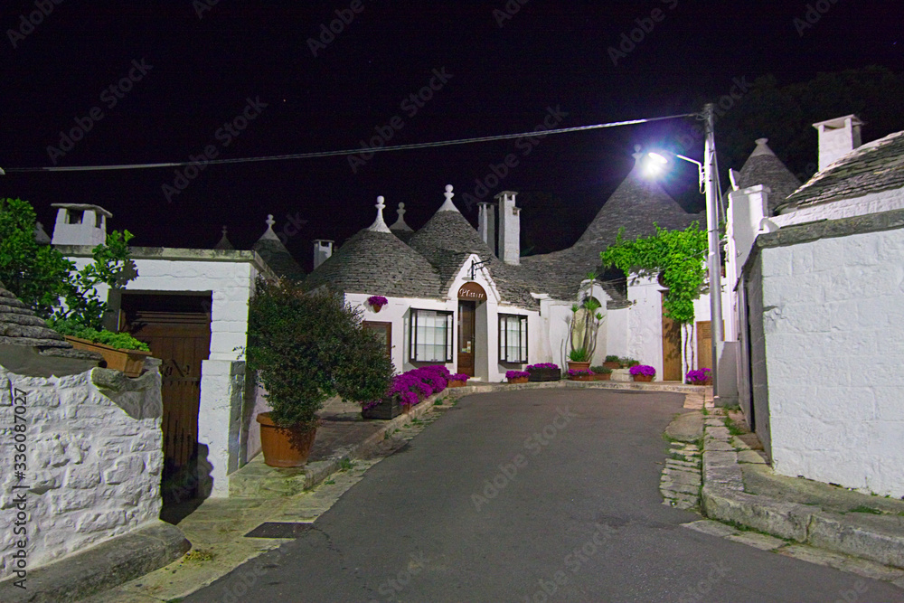 Night view of the streets with the characteristic trulli of the town of Alberobello in Puglia, Italy.