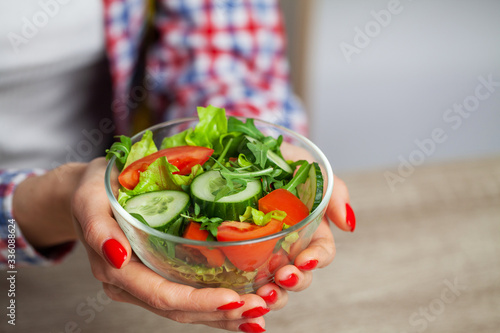 Woman holding fresh vegetable salad in a transparent plate