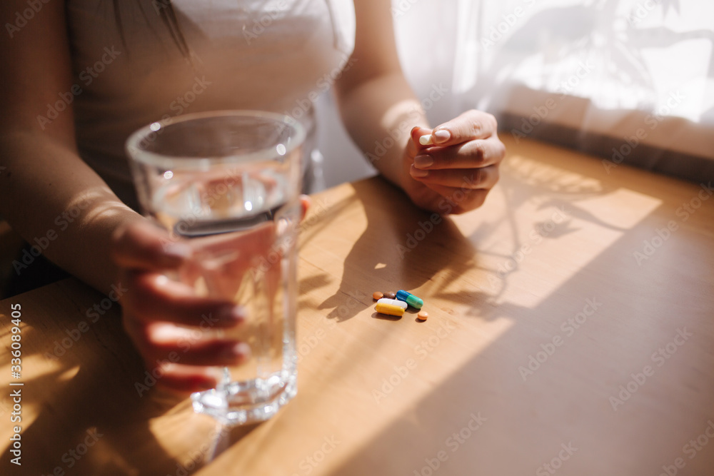 Close up of woman's hands hold pills. Hand with pills and glass of water. Immunity. Vitamines Close up of woman's hands hold pills. Hand with pills and glass of water. Immunity. Vitamines