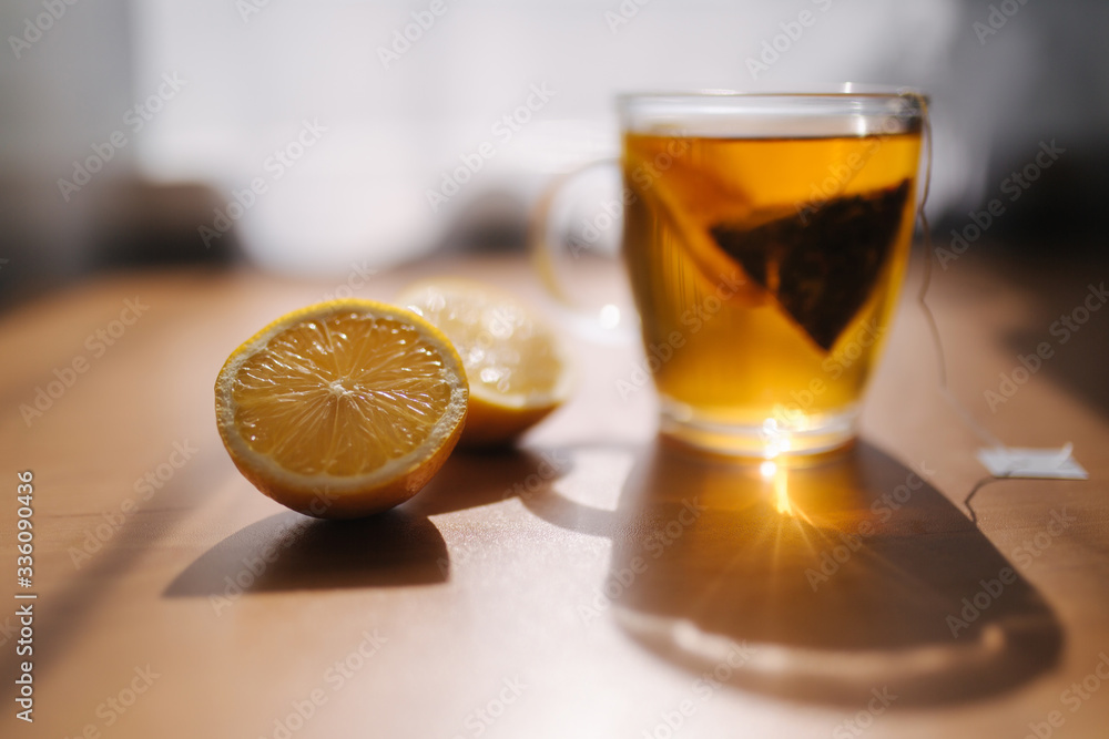 Black tea with lemon on wooden table. Tea bag with lemon slice in cup Black tea with lemon on wooden table. Tea bag with lemon slice in cup