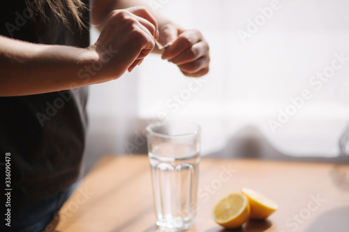 Female's hands put aspirin in glass with water. Coronavirus concept