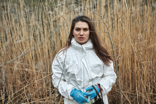 Girl in protective overalls on the nature. Biological protection suit. Personal protective equipment to prevent transmission of the virus. The concept of coronavirus, pandemic, flu and quarantine. © nikolay_voronin
