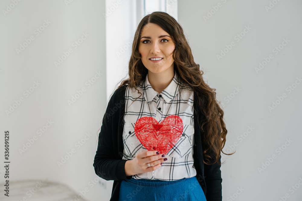 portrait of attractive caucasian smiling woman with long curly brunette hair near the window portrait of attractive caucasian smiling woman with long curly brunette hair near the window