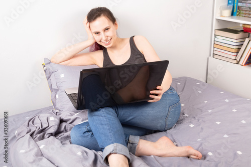 Free Download Concept - work from home, self-isolation. Young girl lies in bed looking into laptop and smiles - GFXLoad