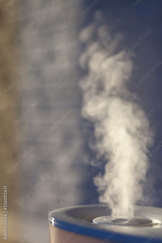 Humidifier spreading steam with white brick background.