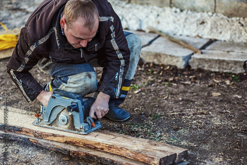 Circular saw for cutting boards into the hands of the builder, the man sawed bars, construction and home renovation, repair and construction tool. Carpenter Using Circular Saw for wood