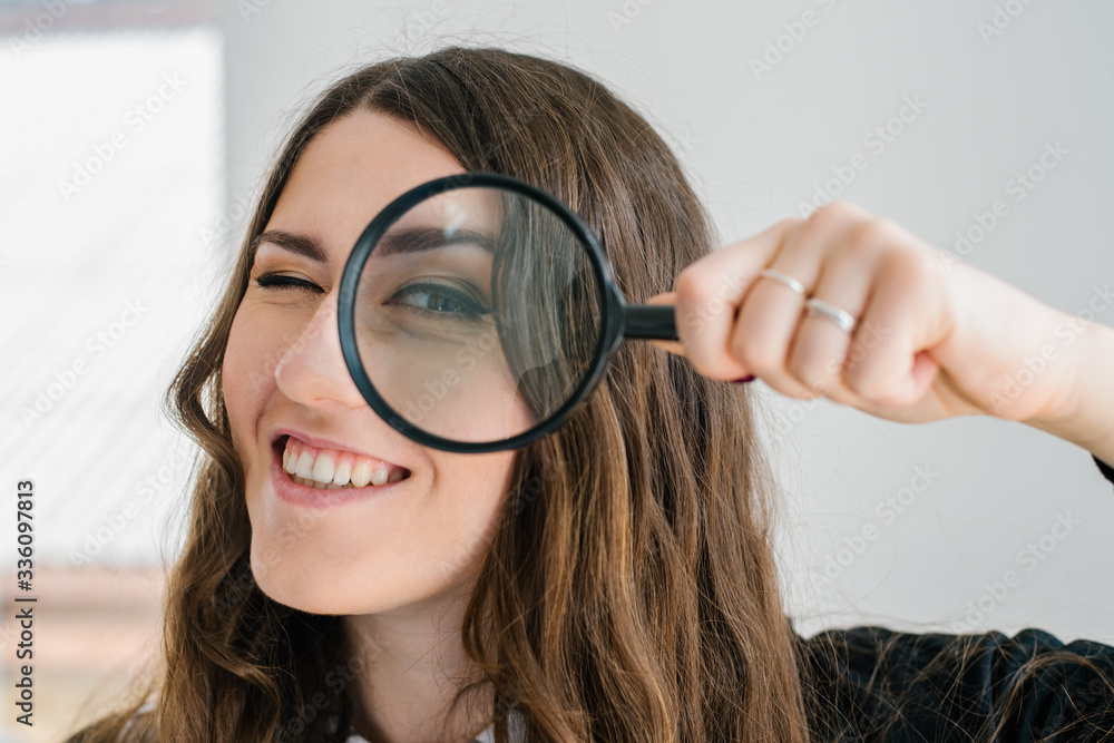 on a gray background young girl looking through a magnifying glass on a gray background young girl looking through a magnifying glass