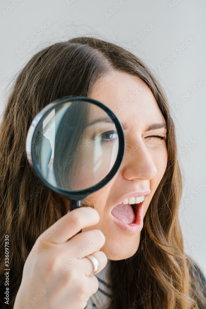 on a gray background young girl looking through a magnifying glass on a gray background young girl looking through a magnifying glass