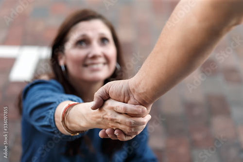 Man giving woman a friendly helping hand to lift her up to help and support her to get her on her feet in fellowship photo