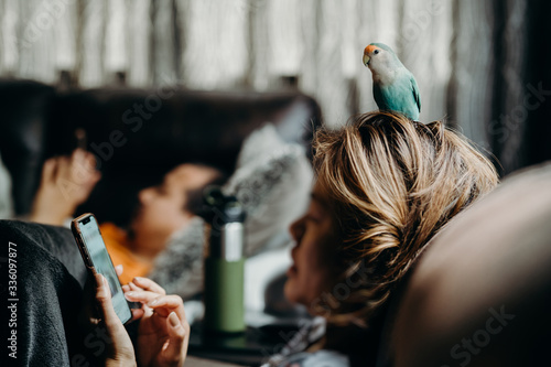 Woman liviing with Lovebird on hand with smart phone in livingroom. photo