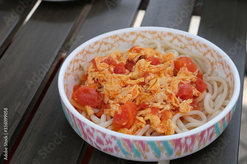 close up tomato and egg noodles in patterned bowl. Traditional Chinese cuisine.