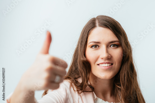 on a gray background young girl showing thumbs up