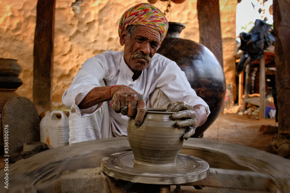 Indian potter at work throwing the potter's wheel and shaping ceramic