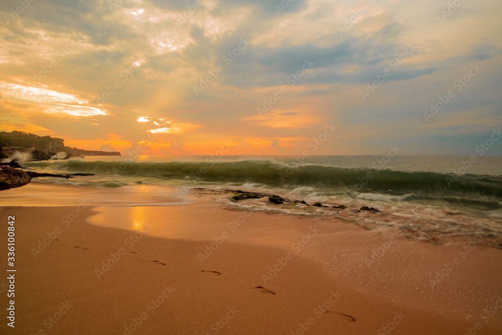 Seascape. Sunset time at the beach. Beach background with footprints in the sand. Tegal Wangi beach, Bali, Indonesia