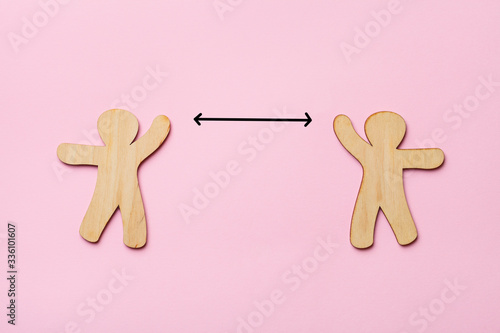 keep distance concept, two wooden people on pink background, preventive measures, infection control photo