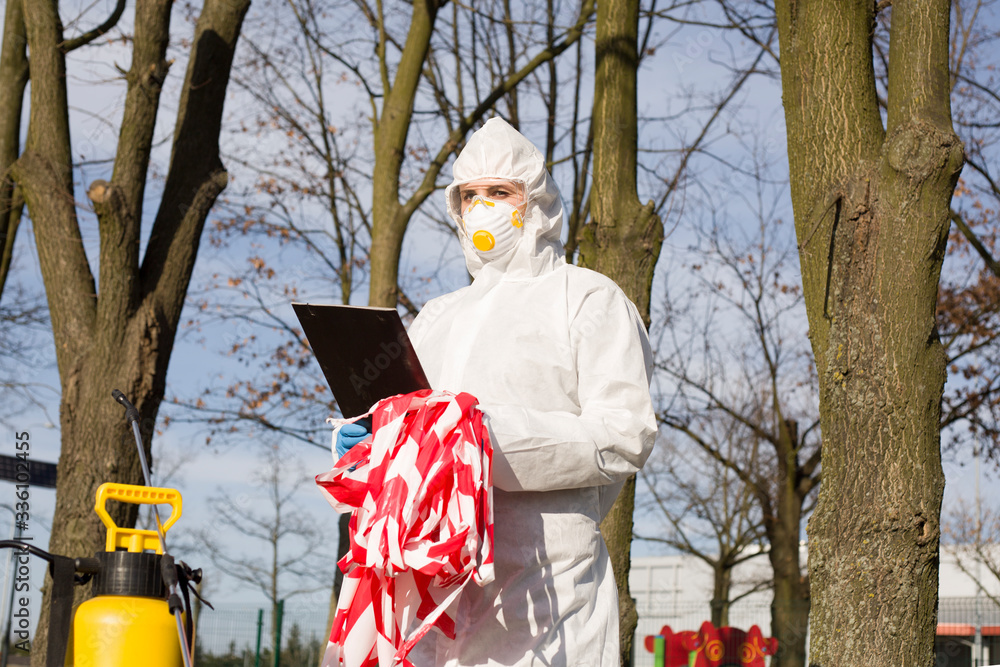 Naklejka premium Postać w kombinezonie ochronnym z taśmą bezpieczeństwa w dłoniach, czyta wytyczne dotyczące dezynfekcji w parku