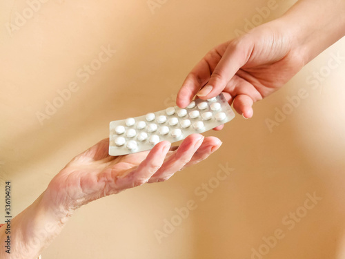  a young mans hand passes a pack of pills to an elderly mans hand. Help old people