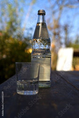 A bottle of water with a water glass selective focus