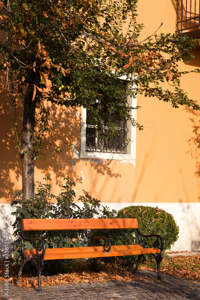 Obraz premium Empty bench against old yellow house in Budapest on Buda side. Buda hills is huge area in West part of Budapest