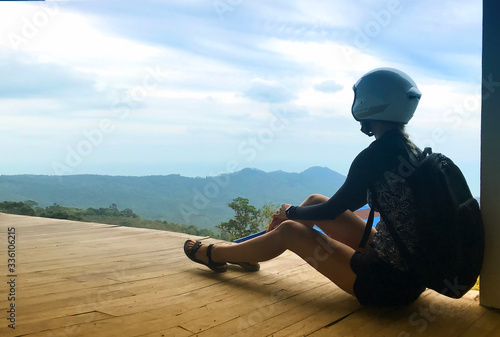The young attractive woman in motorbike helmet sitting and watching on a mountains. Koh Samui. Thailand 