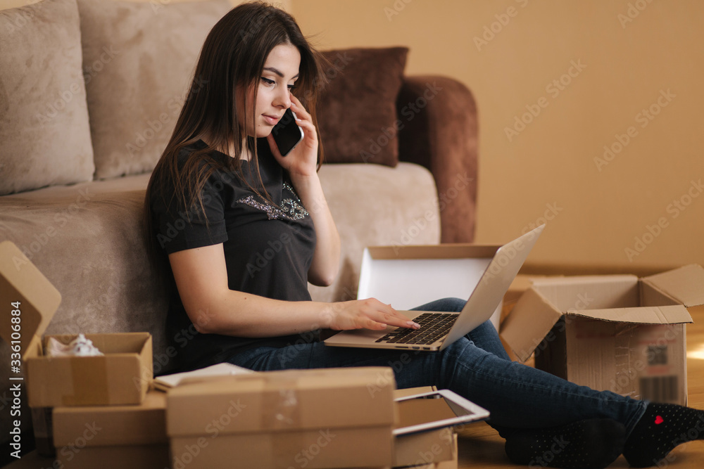 Happy young woman shopping online. Woman use laptop and tablet for searching new goods. Attractive girl surrounded by parcels Happy young woman shopping online. Woman use laptop and tablet for searching new goods. Attractive girl surrounded by parcels