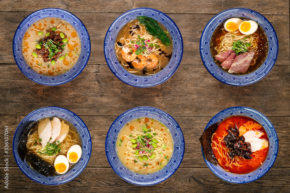 Set of different types of Japanese ramen, tantanmen, shio ramen, shrimp, wood mushrooms, top view on a wooden background, in blue traditional bowls