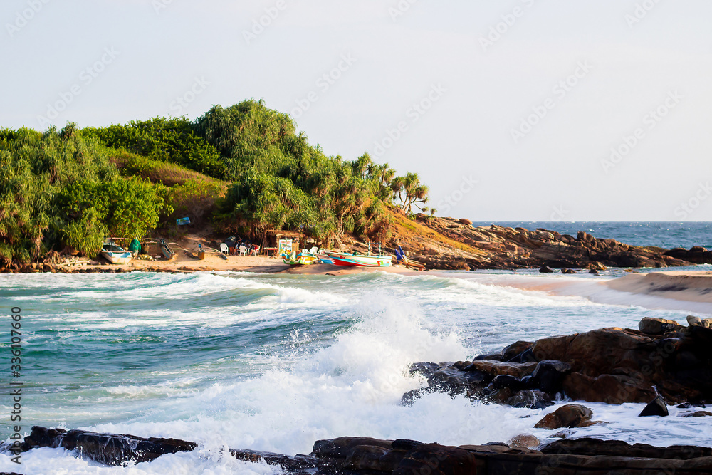 untouched tropical beach with rocks in the water and white waves in Sri Lanka