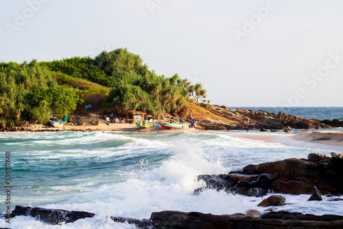 untouched tropical beach with rocks in the water and white waves in Sri Lanka